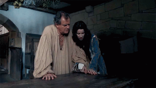 A Man And A Woman Are Standing Next To Each Other In A Dark Room GIF