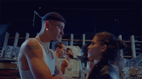 A Man And A Woman Are Standing Next To Each Other In A Dark Room GIF