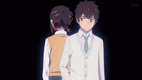 A Man And A Woman Are Standing Next To Each Other In A Dark Room . GIF