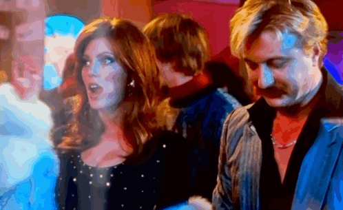 A Man And A Woman Are Standing Next To Each Other In A Dark Room GIF