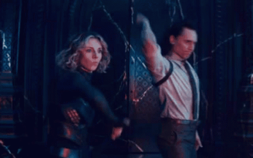 A Man And A Woman Are Standing Next To Each Other In A Dark Room Holding Swords . GIF