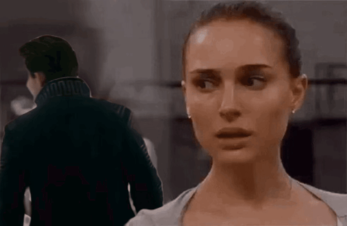A Man And A Woman Are Standing Next To Each Other In A Dark Room . GIF