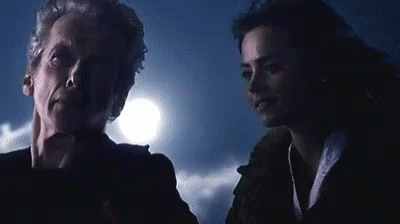 A Man And A Woman Are Standing Next To Each Other In A Dark Room With A Full Moon In The Background . GIF