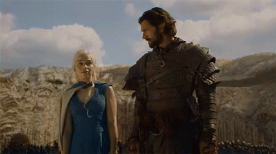 A Man And A Woman Are Standing Next To Each Other In A Field And Holding Hands . GIF