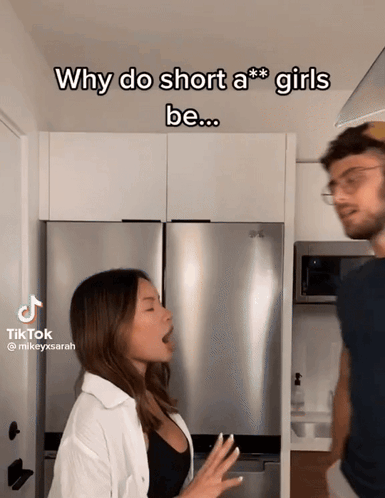 A Man And A Woman Are Standing Next To Each Other In A Kitchen With The Caption Why Do Short A *** Girls Be GIF