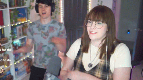 A Man And A Woman Are Standing Next To Each Other In A Living Room . GIF