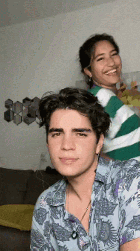 a man and a woman are standing next to each other in a living room and smiling .