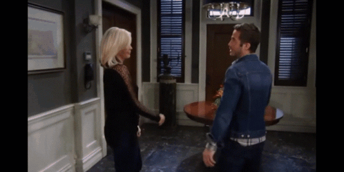 A Man And A Woman Are Standing Next To Each Other In A Living Room GIF