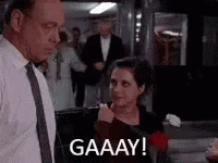 A Man And A Woman Are Standing Next To Each Other In A Room And The Woman Is Holding A Rose . GIF