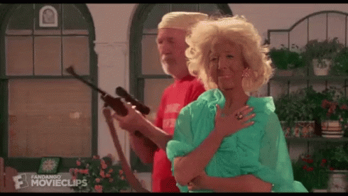 A Man And A Woman Are Standing Next To Each Other In A Room Holding A Gun . GIF