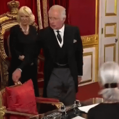A Man And A Woman Are Standing Next To Each Other In A Room . GIF