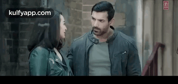 A Man And A Woman Are Standing Next To Each Other In A Room . GIF