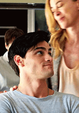 A Man And A Woman Are Standing Next To Each Other In A Room . GIF