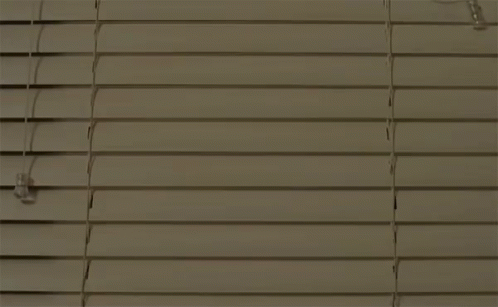 A Man And A Woman Are Standing Next To Each Other In A Room With A Staircase In The Background . GIF