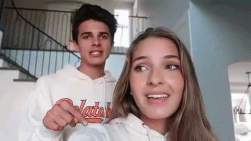 A Man And A Woman Are Standing Next To Each Other In A Room . GIF