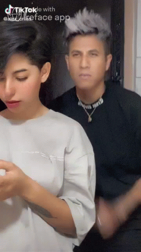 A Man And A Woman Are Standing Next To Each Other In A Tiktok Video . GIF
