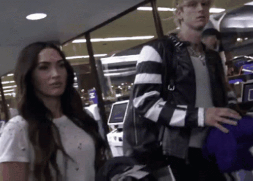 A Man And A Woman Are Standing Next To Each Other In An Airport GIF