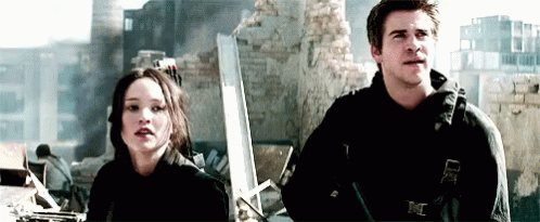 A Man And A Woman Are Standing Next To Each Other In Front Of A Building . GIF