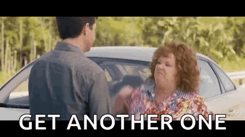 A Man And A Woman Are Standing Next To Each Other In Front Of A Car And The Woman Is Yelling At The Man . GIF