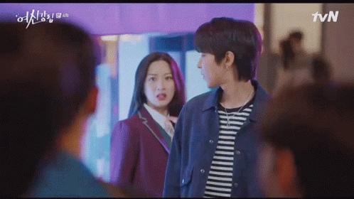 A Man And A Woman Are Standing Next To Each Other In Front Of A Crowd . GIF