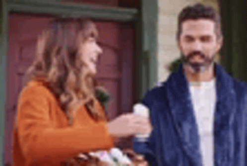 A Man And A Woman Are Standing Next To Each Other In Front Of A Door . GIF