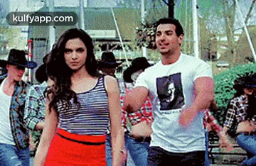 A Man And A Woman Are Standing Next To Each Other In Front Of A Group Of People . GIF