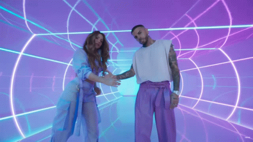 a man and a woman are standing next to each other in front of a neon tunnel