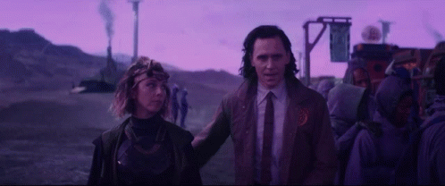 A Man And A Woman Are Standing Next To Each Other In Front Of A Purple Sky . GIF