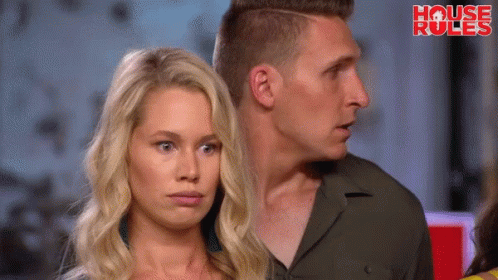 A Man And A Woman Are Standing Next To Each Other In Front Of A Sign That Says " House Rules " GIF