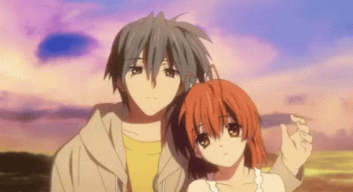 A Man And A Woman Are Standing Next To Each Other In Front Of A Sunset . GIF