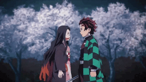 A Man And A Woman Are Standing Next To Each Other In Front Of A Tree . GIF
