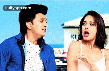 A Man And A Woman Are Standing Next To Each Other In Front Of An Ice Truck . GIF