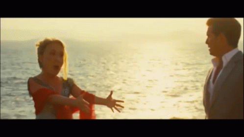 A Man And A Woman Are Standing Next To Each Other In Front Of The Ocean GIF