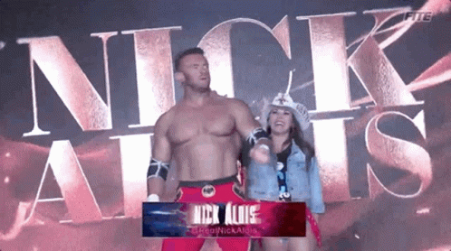 A Man And A Woman Are Standing Next To Each Other In Front Of The Word Nick Allis GIF