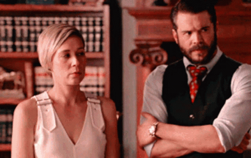 A Man And A Woman Are Standing Next To Each Other GIF