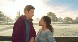 A Man And A Woman Are Standing Next To Each Other On A Balcony And Kissing . GIF