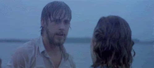 A Man And A Woman Are Standing Next To Each Other On A Beach Looking At Each Other . GIF