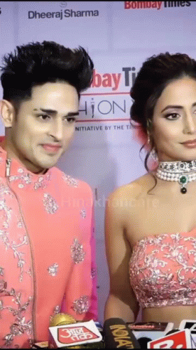 a man and a woman are standing next to each other on a red carpet in front of a sign that says bombay times