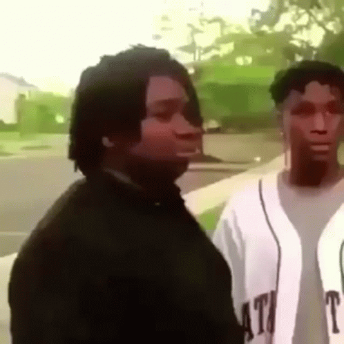 A Man And A Woman Are Standing Next To Each Other On A Sidewalk And Looking At Each Other . GIF