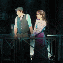 A Man And A Woman Are Standing Next To Each Other On A Stage . GIF