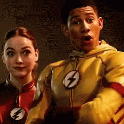 A Man And A Woman Are Standing Next To Each Other . The Man Is Wearing A Yellow Flash Suit . GIF