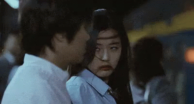 A Man And A Woman Are Standing Next To Each Other . The Woman Is Making A Funny Face . GIF