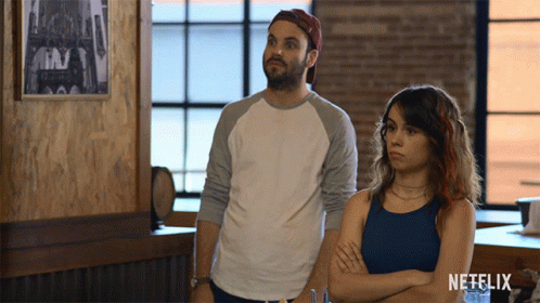 Man And Woman Standing Next To Netflix Logo GIF