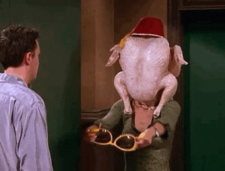 A Man And A Woman Are Standing Next To Each Other With A Turkey On Their Head . GIF