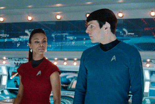 A Man And A Woman Are Standing Next To Each Other With The Man Wearing A Blue Shirt With The Letter A On It GIF
