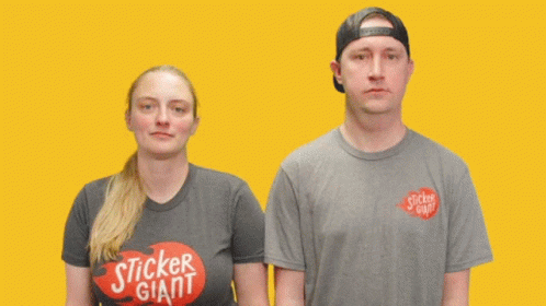 A Man And A Woman Are Standing Next To Each Other With The Word Awkward Written On Their Shirts GIF