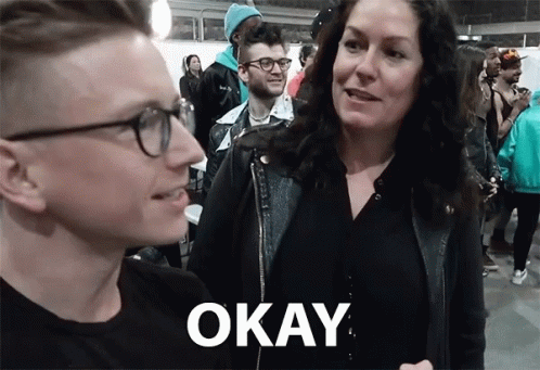 A Man And A Woman Are Standing Next To Each Other With The Word Okay On The Bottom Right GIF