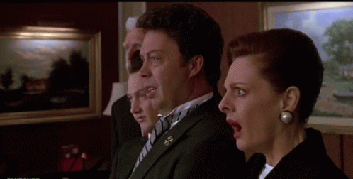 A Man And A Woman Are Standing Next To Each Other With Their Mouths Open In A Room . GIF
