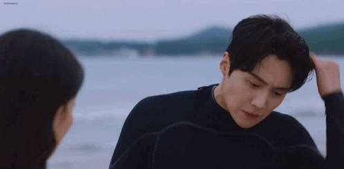 A Man And A Woman Are Standing On The Beach Looking At Each Other . GIF