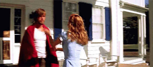 A Man And A Woman Are Standing Outside Of A White House . GIF